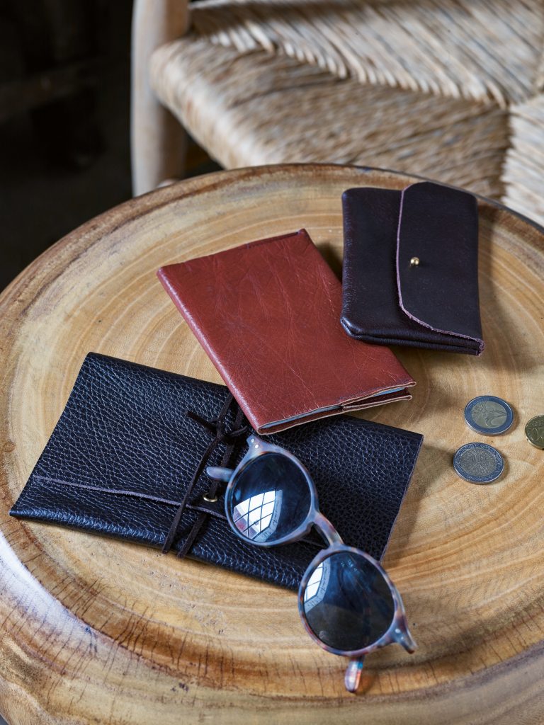 Solbrilleetui, passlomme og lommebok på et bord.