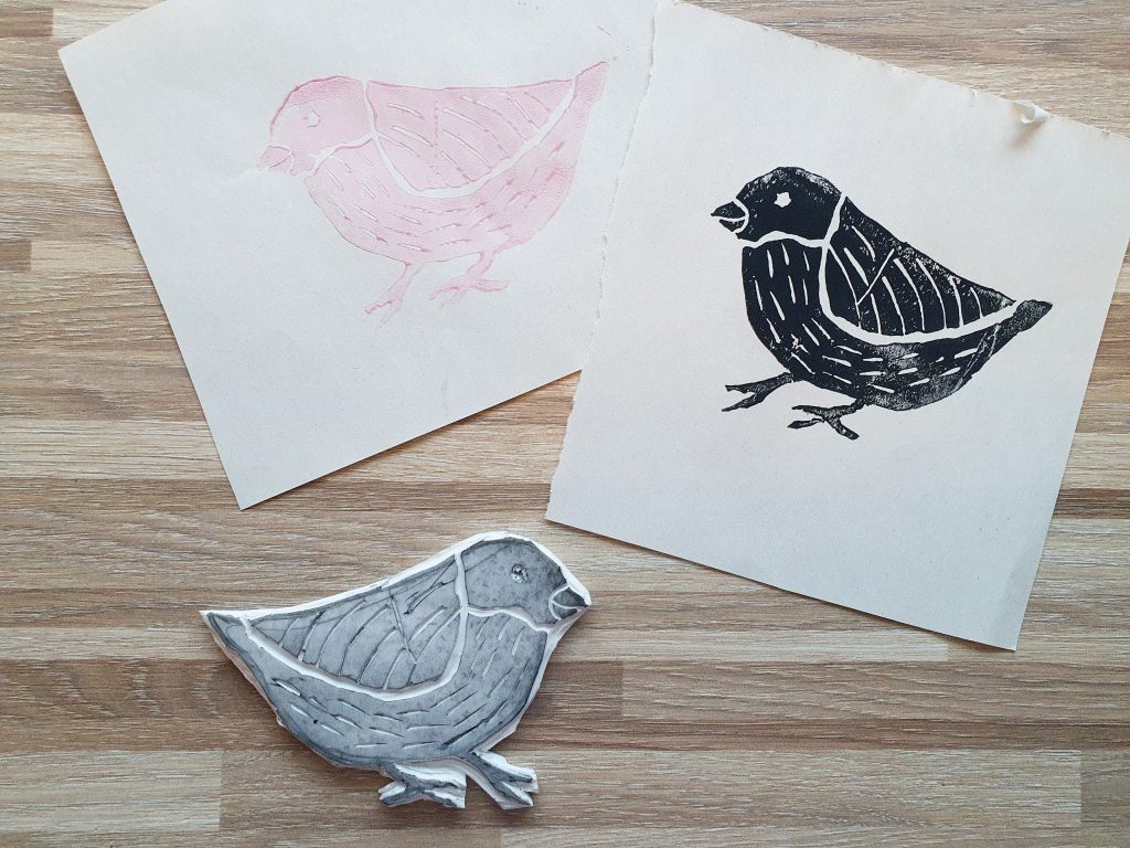 Fuglestempel, og to versjoner av trykk med fuglen, rosa og sort.