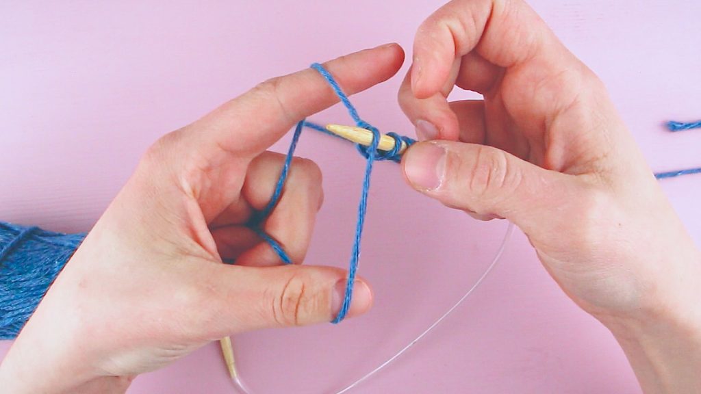 To hender viser hvordan man legger opp en maske i strikketøyet.
