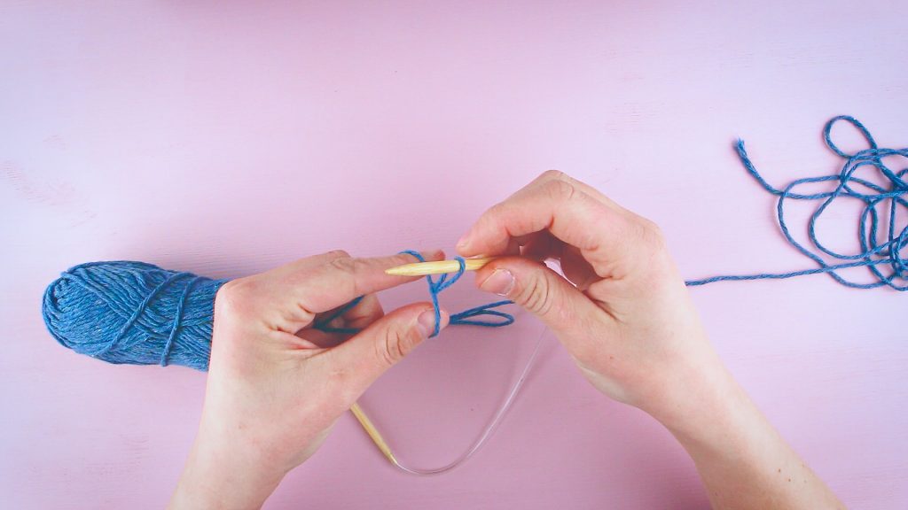 To hender viser hvordan man legger opp en maske i strikketøyet.