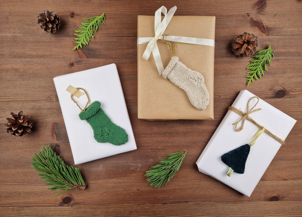 To julegaver med julestrømper som er hvite og grønne, og en gave med et hjemmesydd tre.