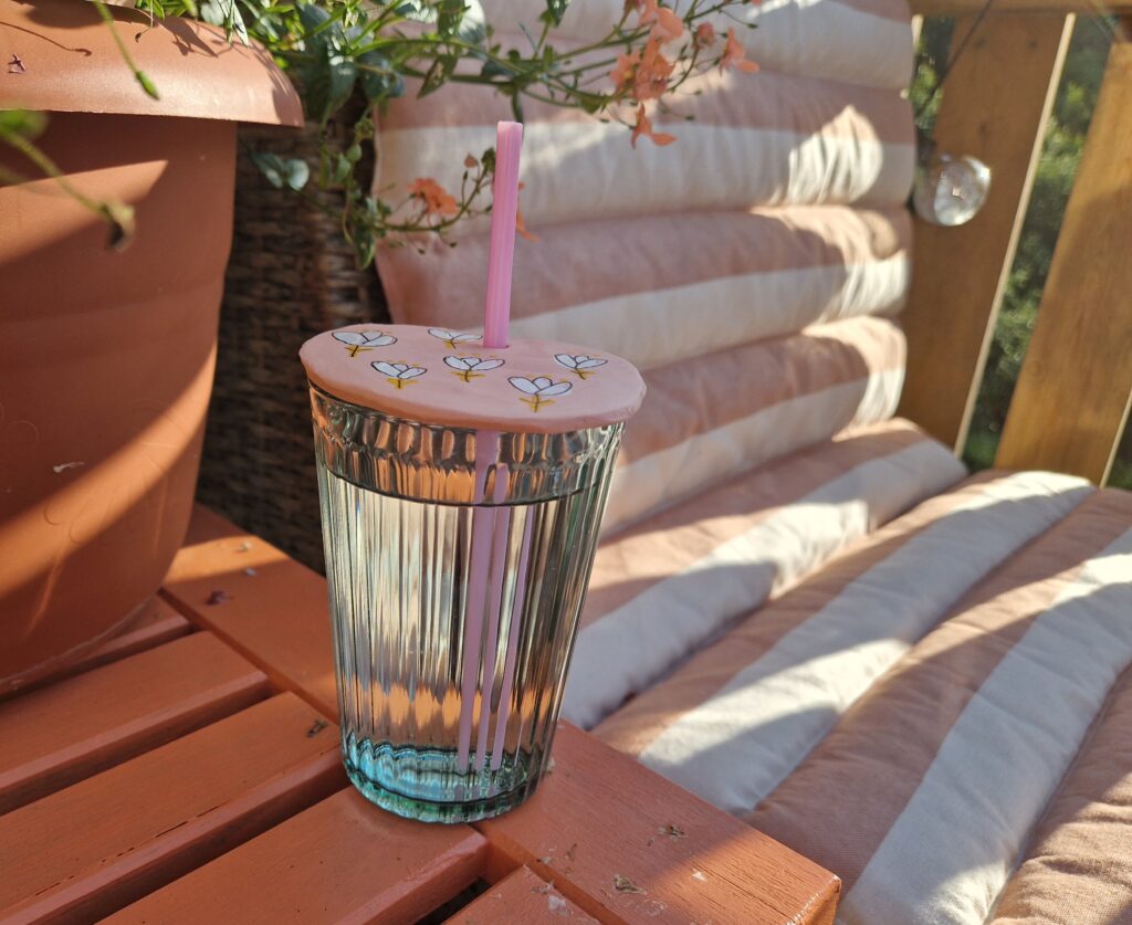 Glass med rosa lokk, på et ferskenfarget bord.